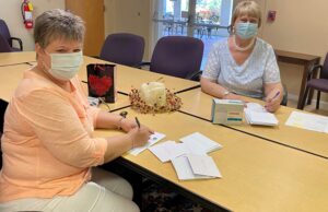 Two women writing cards to send for First UMC of Naples