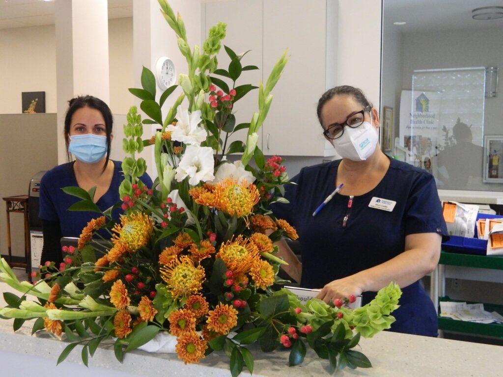 Two hospital workers pose with a bouquet of flowers from First UMC