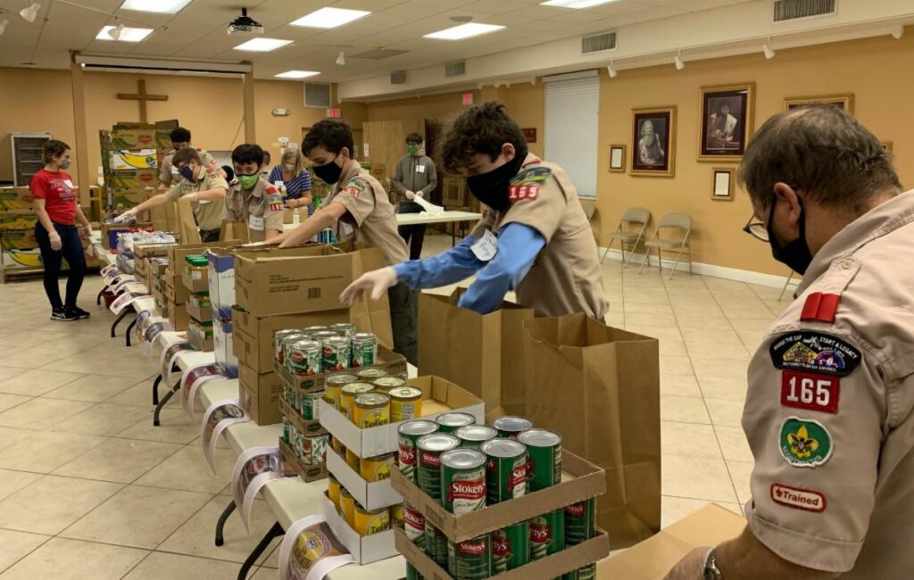 A row of boyscouts packaging food drive goods